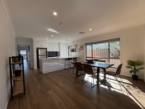 Una cocina moderna con armarios blancos, una isla central y un comedor con mesa y sillas.