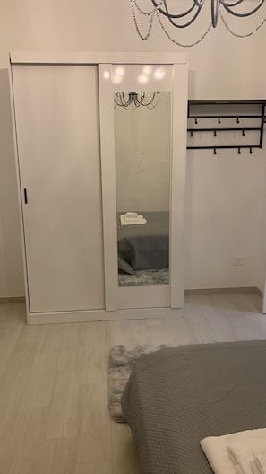 Un dormitorio con armario, cama, espejo y candelabro.