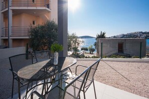 Ein Balkon mit Tisch und Stühlen, der auf ein Gewässer und einen entfernten Hügel blickt.