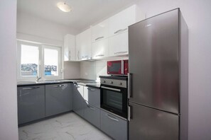 Eine moderne Küche mit Edelstahlgeräten, weißen Schränken und einem Fenster mit Blick.