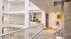 A multi-level interior with a central atrium, white railings, and a staircase.