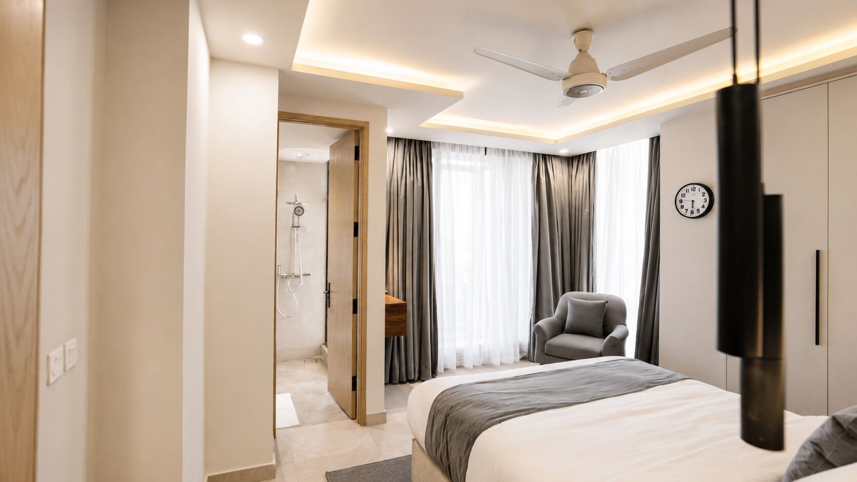 A modern hotel room with a bed, a chair, a desk, and a shower area.