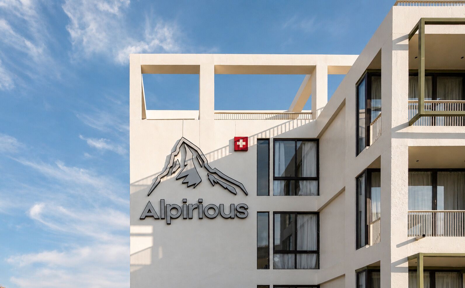 A building with a mountain logo and the name 'Alpirious' on the facade.