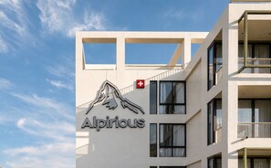 A building with a mountain logo and the name 'Alpirious' on the facade.
