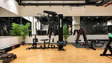 Een sportschool met trainingsapparatuur, een spiegelwand en potplanten.