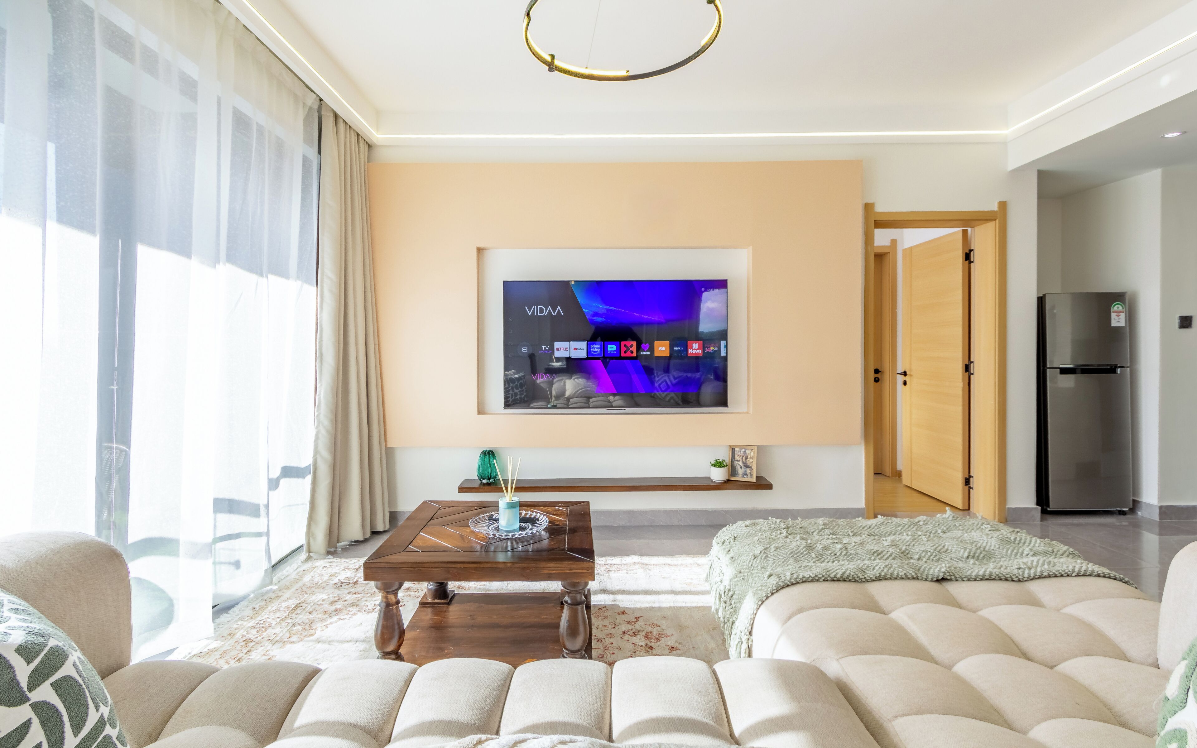 A living room with a TV, sofa, coffee table, and a door leading to another room.
