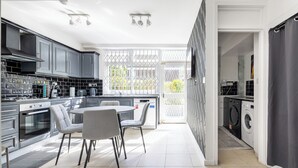 Una cocina moderna con armarios grises, un comedor con mesa y sillas, y un área de lavandería con lavadora.