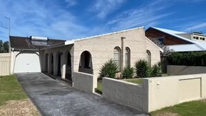 Un bâtiment d’un seul étage, doté d’un garage, d’une allée couverte et d’un jardin aménagé à l’avant.