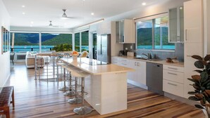 Eine moderne Küche mit einer großen Kochinsel, Barhocker und Meerblick.
