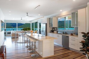 Eine moderne Küche mit einer großen Kochinsel, Barhocker und Meerblick.