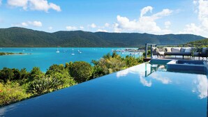 Ein Infinity-Pool mit Blick auf ein türkisfarbenes Meer und Segelboote.