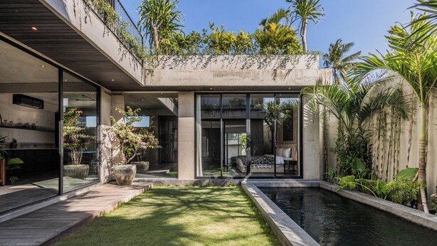A modern house with a swimming pool, a covered patio, and lush greenery. - Seseh House by Alfred in Bali (Cemagi)