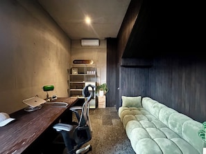A room with a wooden desk, a green lamp, a chair, a sofa, a plant, and a sign reading 'SESEI HOUSE'. - Seseh House by Alfred in Bali (Cemagi)