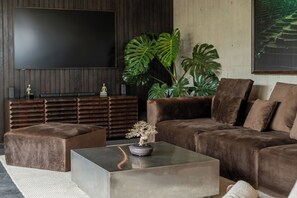 Ein modernes Wohnzimmer mit einer Couch, einem Hocker und einem Couchtisch.