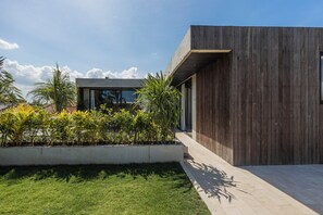 Ein modernes Gebäude mit Holzfassade, einem Betonbereich und einem gepflegten Garten mit verschiedenen Pflanzen.