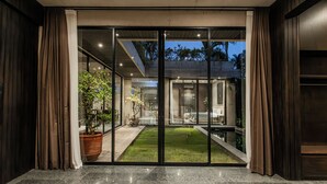 A modern hotel entrance with glass doors, a well-lit interior, and a visible outdoor garden area. - Seseh House by Alfred in Bali (Cemagi)