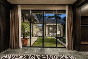 Ein moderner Hotel-Eingangsbereich mit Glastüren, einem gut beleuchteten Innenraum und einem sichtbaren Gartenbereich.