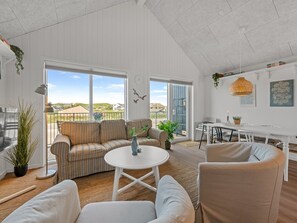 Ein geräumiger Wohnbereich mit Sofa, Sesseln, einem Esstisch und Blick ins Freie.