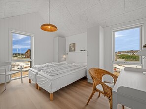 Une chambre à coucher comprenant un lit, une chaise, un bureau et un luminaire suspendu.