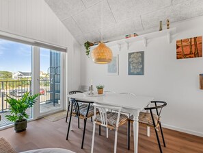 A dining area with a white table, black chairs, and a hanging light fixture. - "Ila" - 350m from the sea by Interhome (Ringkøbing)