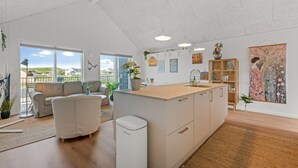 En rummelig opholdsstue med et køkken, en sofa og udsigt til det fri.