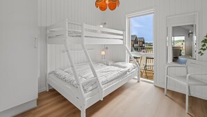 Et soveværelse med køjeseng, udsigt over landskabet, et skrivebord og en hængende lampe.