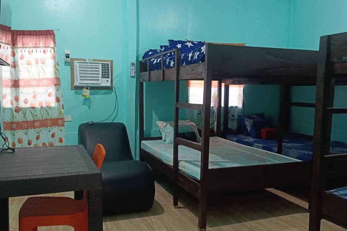 A room with bunk beds, a desk, a chair, and a window with curtains.