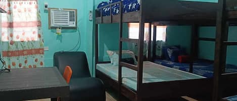 A room with bunk beds, a desk, a chair, and a window with curtains.