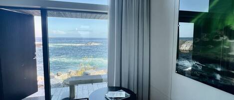 A modern living room with a sofa, a small table, and a view of the ocean.
