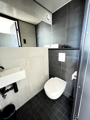 Un baño moderno con un lavamanos blanco, inodoro y zona de ducha.