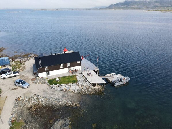 A coastal building with a dock, a small boat, and parked cars.