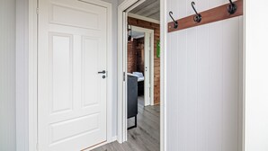 A hallway with a white door, a wooden bench, and a coat rack.