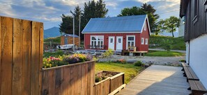 A red house with a white door, a wooden deck, and a garden with colorful flowers. - Arctic Lofoten Mini Retreat - Enjoy the silence! (Vestvågøy)