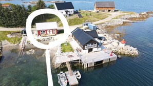 An aerial view of a waterfront property with a dock, a small boat, and a house with a red roof.