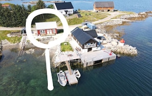 An aerial view of a waterfront property with a dock, a small boat, and a house with a red roof.