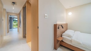 Un dormitorio moderno con cabecera de madera, una mesita de noche y vistas al exterior.