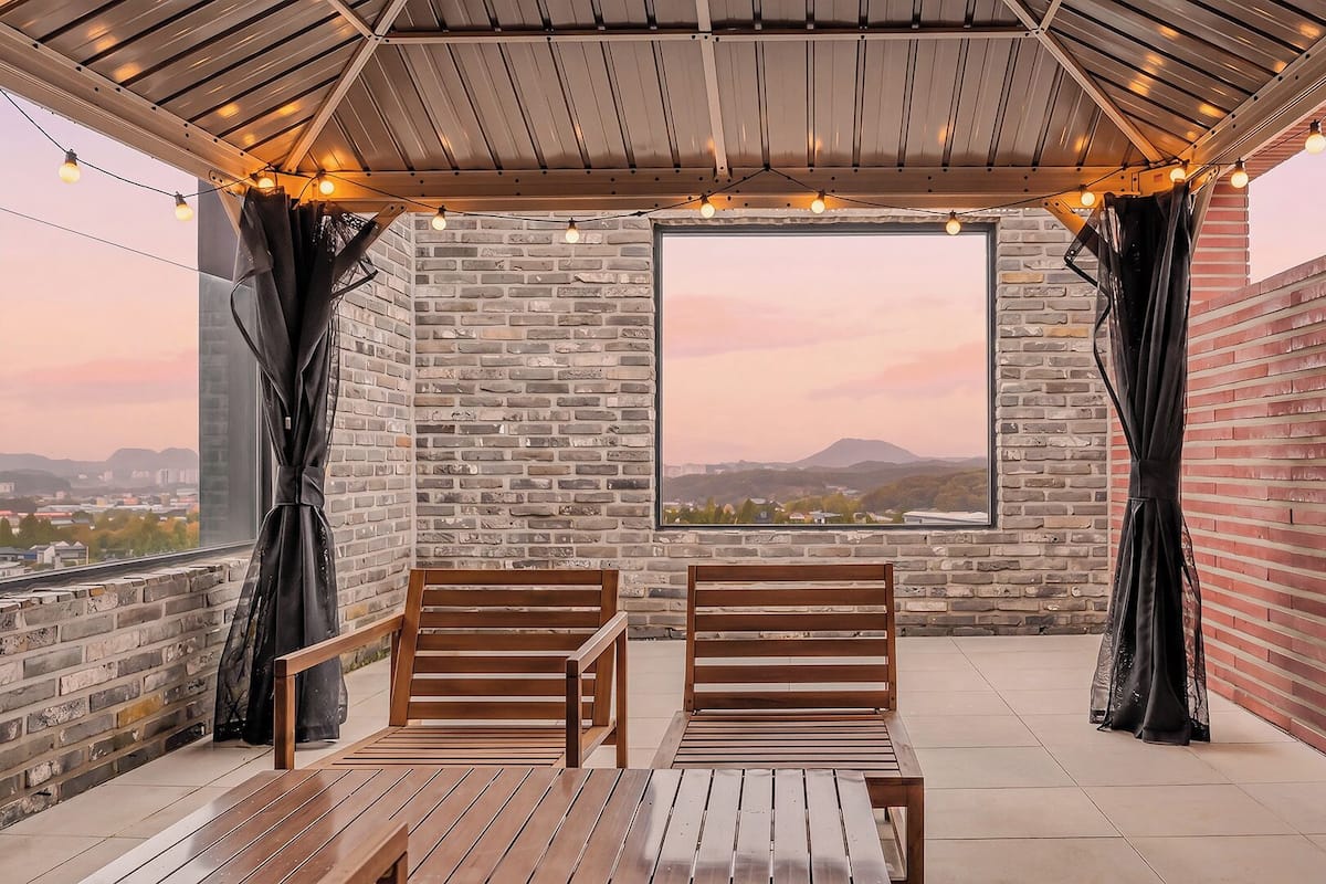 A covered outdoor seating area with a view of a cityscape and mountains.