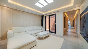 A modern living room with a sectional sofa, a small ottoman, and a large window with skylights. - Chuncheon Stay Moon (Chuncheon)
