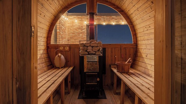 Una sauna de madera con bancos, un calentador y una pared de ladrillo.