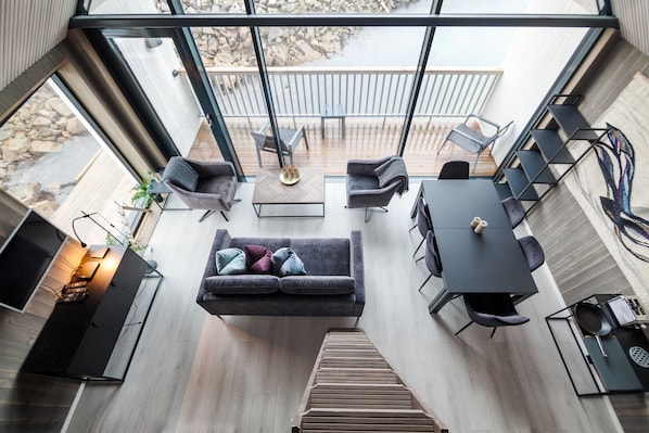 A modern interior with a sofa, dining table, chairs, and a staircase leading to an outdoor area.