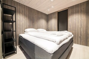 Une chambre à coucher moderne avec un lit, une étagère noire et des murs en bois.