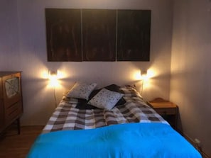 Une chambre à coucher comprenant un lit, deux tables de chevet, une commode et des lampes fixées au mur.