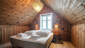 Una habitación con paneles de madera, una cama, una araña y un ventanal.