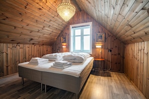 A wooden-paneled room with a bed, a chandelier, and a window. - Arctic Lofoten Retreat - Enjoy the silence! (Vestvågøy)