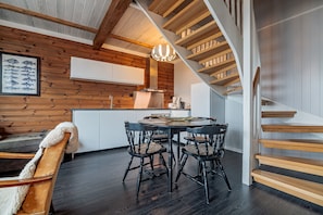 Une cuisine moderne avec des murs en bois, une table à manger ronde et un escalier.