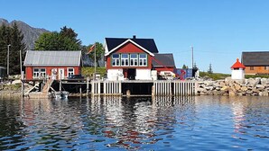 Una propiedad frente al mar con muelle, una casa roja y un faro.