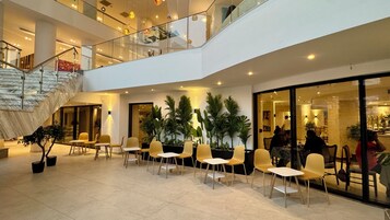 Um espaço interno com vários níveis, áreas de estar, escadas e portas de vidro que dão para outros ambientes.