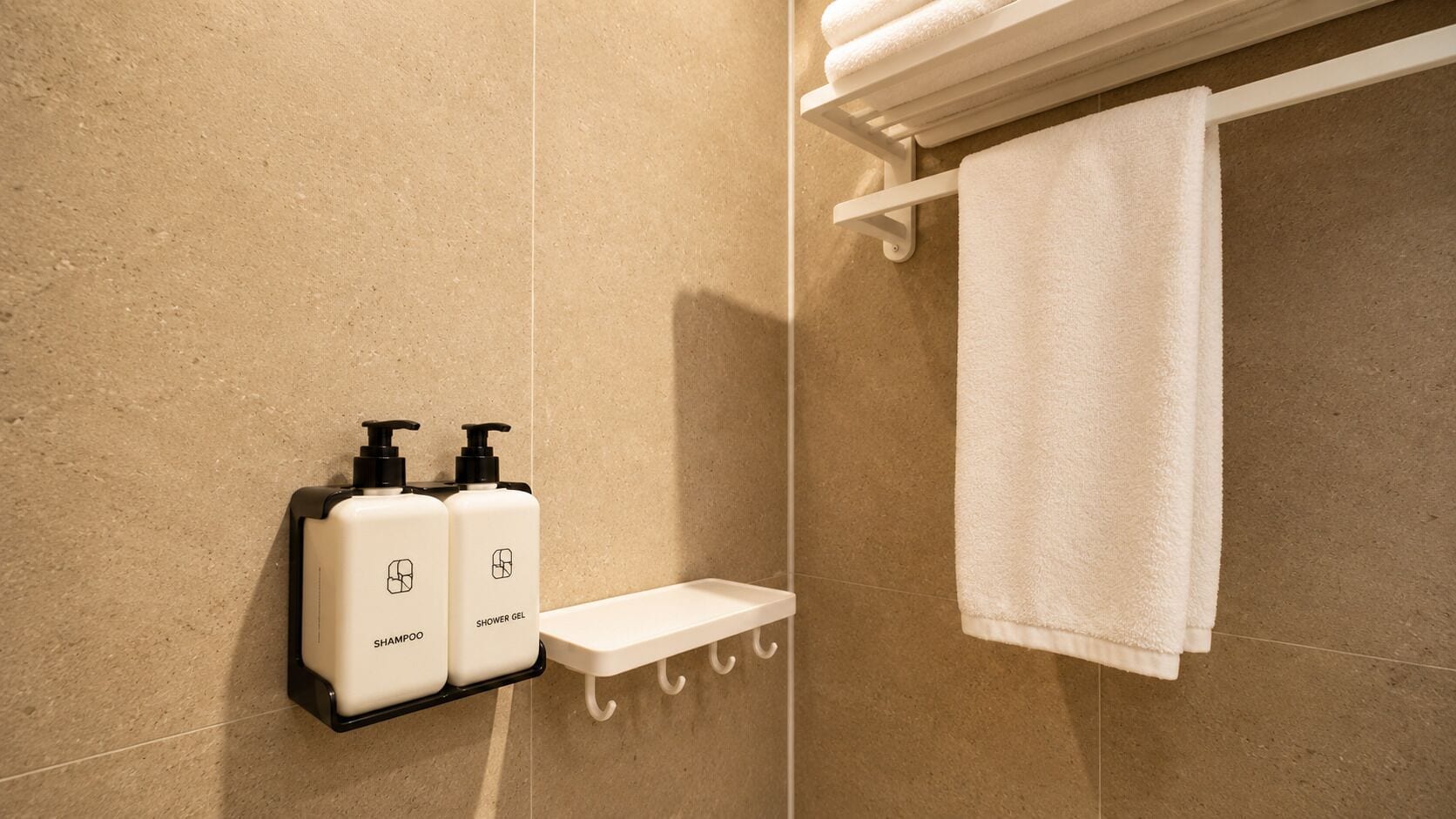 Een badkamer met een douche, een handdoekhouder en twee flessen shampoo en douchegel.