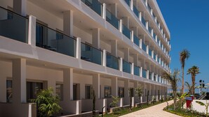 Un hotel de varios pisos con balcones, un espacio al aire libre cubierto y cielo despejado.