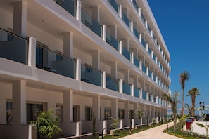 A multi-story hotel with balconies, a covered outdoor area, and a clear sky.